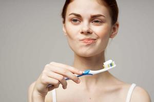 mulher com uma escova de dente dentro mão manhã higiene isolado fundo foto