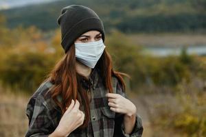 lindo mulher com uma médico mascarar em dela face e dentro caloroso cápsulas ao ar livre dentro a floresta foto