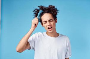 bonito cara com encaracolado cabelo em uma azul fundo retrato fechar-se emaranhado cachos foto