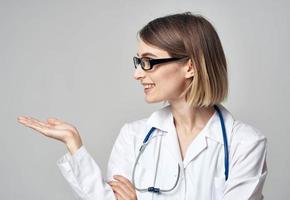 médico com uma estetoscópio mostra dele mão para a lado em uma cinzento fundo cópia de espaço foto