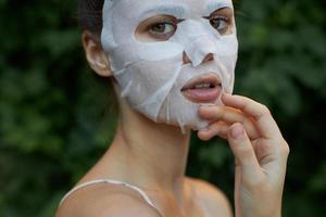 lindo mulher anti-rugas mascarar toque seu face com seu mão pele Cuidado folhas dentro a fundo foto