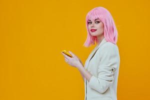 mulher com Rosa cabelo falando em a telefone em uma amarelo fundo foto