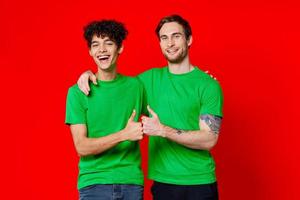 dois homens abraçando dentro verde Camisetas em uma vermelho fundo foto