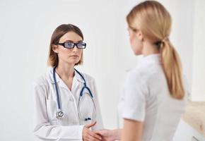 médico dentro uma médico vestido com uma estetoscópio e uma paciente dentro uma branco camiseta costas Visão foto