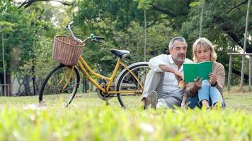 casal maduro lendo um livro em um parque foto