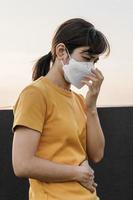 jovem ásia mulher vestindo n95 respiratório mascarar proteger e filtro pm2.5 ou particulado importam contra mau ar poluição dentro cidade. ar qualidade índice, aqi, pouco saudável, cuidados de saúde conceito foto