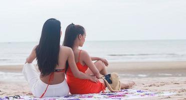duas lindas mulheres felizes sentadas na praia