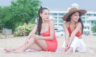 duas lindas mulheres felizes sentadas na praia