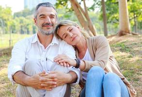 casal sênior caucasiano sentado no gramado do parque foto