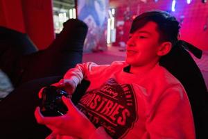 adolescente Garoto jogador jogar controle vídeo jogos console dentro vermelho jogos sala. foto