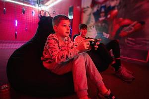 dois Rapazes gamers jogar controle vídeo jogos console dentro vermelho jogos sala. foto