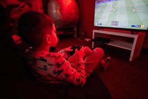 Garoto jogador jogar controle futebol vídeo jogos console dentro vermelho jogos sala. foto