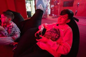 dois Rapazes gamers jogar controle vídeo jogos console dentro vermelho jogos sala. foto