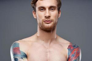 retrato do uma desportivo homem com uma bombeado tronco tatuagem loiro modelo cortada Visão foto