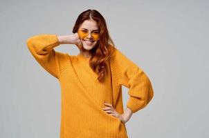 bonita mulher dentro uma amarelo suéter moda óculos luz fundo foto