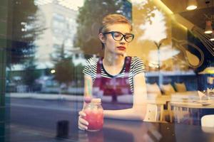 bonita mulher com óculos sentado dentro uma restaurante a partir de uma coquetel solidão estilo de vida foto