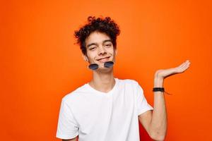 alegre cara dentro uma branco camiseta Sombrio óculos moda laranja fundo foto