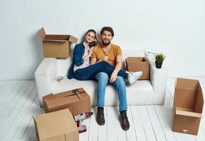 casado casal em uma branco sofá dentro a quarto interior com caixas do comunicação coisas foto