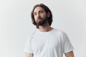 retrato do uma homem com uma Preto Grosso barba e grandes cabelo dentro uma branco camiseta em uma branco isolado fundo emoção do tristeza e anseio foto