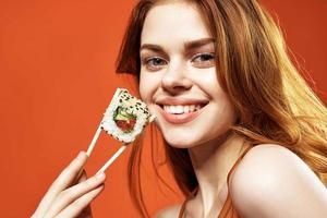 alegre mulher comendo Sushi ásia Comida vermelho fundo foto