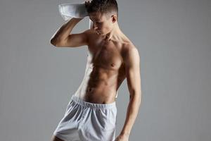 Atlético homem com bombeado acima abdômen dentro branco calção lenços suor com uma toalha foto