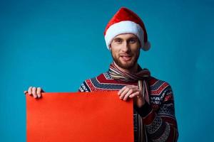 emocional homem dentro uma santa chapéu segurando uma bandeira feriado azul fundo foto