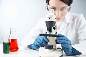 mulher olhando através uma microscópio químico solução laboratório pesquisa biotecnologia foto
