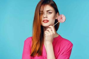 alegre mulher dentro uma Rosa camisa pirulito dentro mãos emoções luxo foto