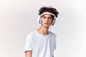 jovem homem com fones de ouvido ouvindo para música Novo tecnologia branco camiseta luz fundo foto