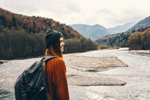 retrato do mulher viajante dentro montanhas ao ar livre perto rio panorama cortada Visão foto