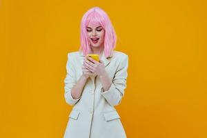 mulher com uma telefone dentro dela mãos Rosa cabelo estúdio amarelo fundo foto