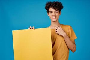 alegre cara com encaracolado cabelo amarelo poster brincar azul fundo foto