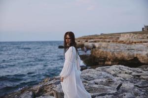 mulher com molhado cabelo dentro uma vestir em a pedregoso costa do a oceano foto