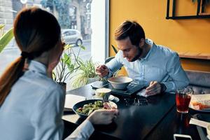 uma homem e uma mulher dentro uma camisa tendo jantar às uma mesa dentro uma restaurante interior dentro a fundo quente Comida bebidas foto