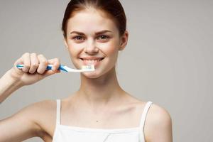 bonita mulher pasta de dentes escovar dentes dental saúde luz fundo foto