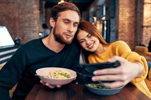 jovem casal dentro uma restaurante faz uma selfie em a telefone comunicação foto