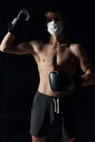 boxer dentro uma médico mascarar em uma Preto fundo luvas atleta nu tronco modelo fisiculturista foto