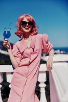 atraente mulher desfrutando uma colorida coquetel em a panorâmico Visão hotel terraço feliz fêmea relaxante foto