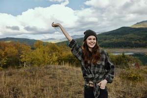 feliz mulher com uma elevado mão em natureza dentro a outono floresta dentro a montanhas foto