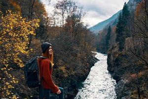 mulher caminhante com mochila dentro a montanhas outono floresta foto