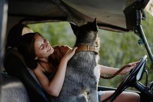 mulher e dela rouco cachorro alegremente viajando dentro carro sorrir com dentes outono andar com bicho de estimação, viagem com cachorro amigo foto