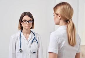 médico dentro uma médico vestido com uma estetoscópio e uma paciente dentro uma branco camiseta costas Visão foto