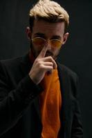 à moda homem dentro laranja suéter endireita óculos em dele face foto