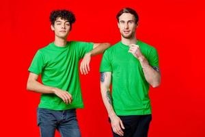 dois alegre amigos dentro verde Camisetas alegria do comunicação vermelho fundo foto