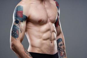 desportivo homem com bombeado acima abdômen cortada Visão do tatuagem em braços fechar-se foto