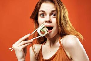 alegre mulher comendo Sushi ásia Comida vermelho fundo foto