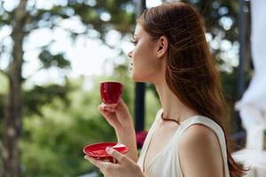 lindo mulher dentro uma branco vestir bebidas café ao ar livre dentro uma cafeteria relaxamento conceito foto