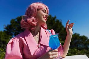 atraente mulher bebendo uma coquetel em a terraço feliz fêmea relaxante foto