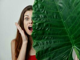 emocional mulher cobre metade do dela face com verde folha vermelho roupa de banho foto