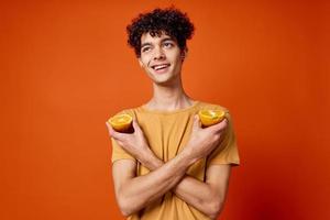 alegre cara com encaracolado cabelo e segurando a laranja isolado fundo foto